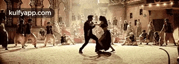a man and a woman are dancing in front of a crowd of people in a room .