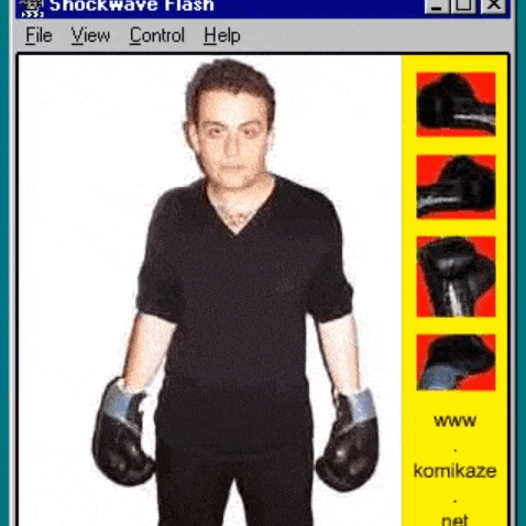 a man wearing boxing gloves and a black shirt is standing in front of a computer screen .
