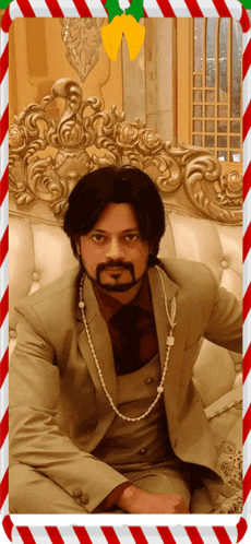a man in a suit sits on a couch with a candy cane in the background