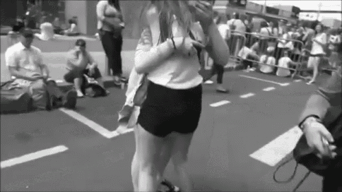 a black and white photo of a woman in shorts standing in a parking lot .