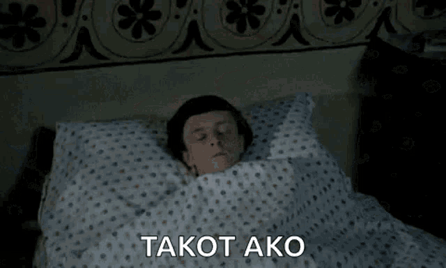 a man is laying in bed with his eyes closed and the words takot ako written on the bottom .