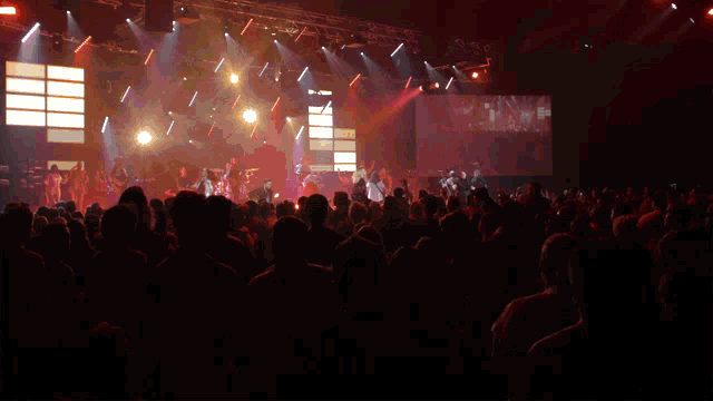 a man singing into a microphone with a crowd behind him