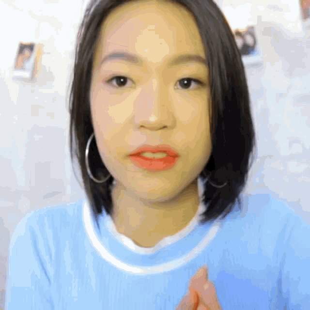 a woman wearing hoop earrings and a light blue shirt
