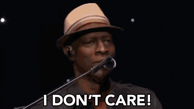 a man in a hat is singing into a microphone and saying `` i do n't care '' .