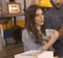 a man and a woman are sitting at a table with a cake in the background .