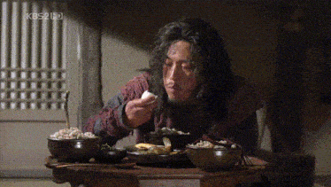 a man is sitting at a table with bowls of food and a kbs2 hd watermark
