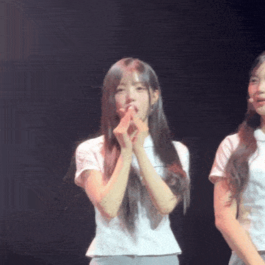 a girl with long hair is making a heart shape with her fingers