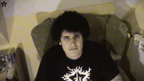 a young man is sitting in a chair wearing a black shirt with a white star on it .