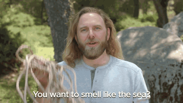 a man with long hair and a beard is holding a rope and says you want to smell like the sea