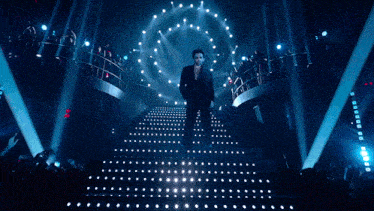 a man in a mask is walking up a set of stairs in a dark room