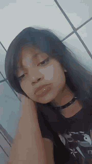 the girl is wearing a choker and a black shirt and looking at the camera .