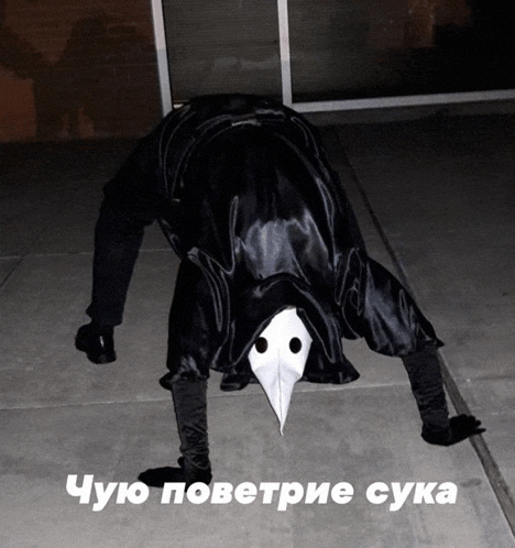 a person in a plague doctor costume is doing a handstand on the ground