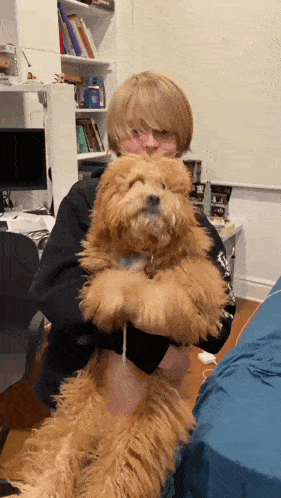 a person holding a small brown dog in their arms with their eyes closed