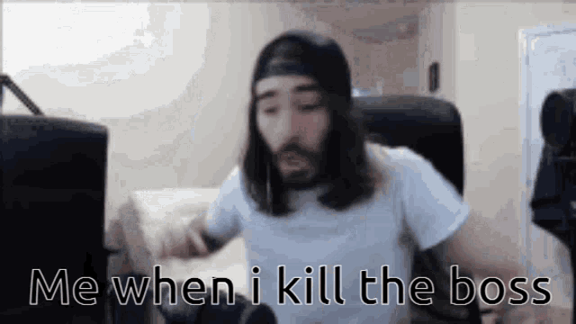a man with long hair and a beard is sitting in front of a computer screen .