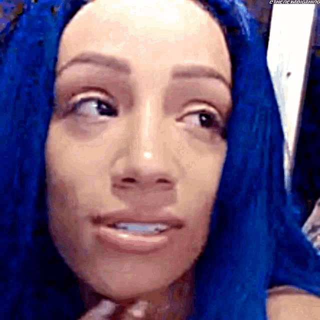 a close up of a woman 's face with blue hair and a toothbrush in her mouth .