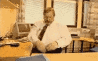 a man in a white shirt and tie is sitting at a desk in an office