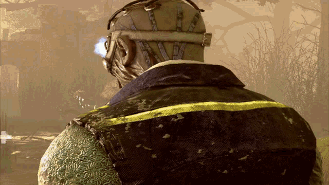 the back of a man wearing a gas mask and a dirty vest