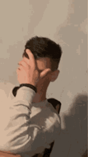 a young man is covering his face with his hand .