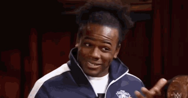 a man in a blue and white jacket is smiling and making a funny face .
