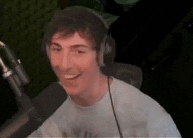 a young man wearing headphones is sitting in front of a microphone .