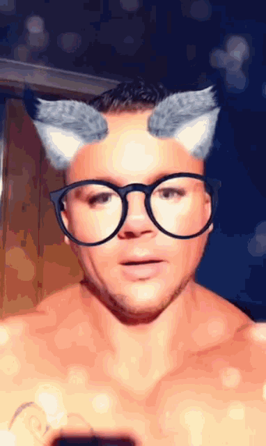a man wearing glasses and cat ears looks at the camera