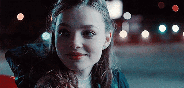 a young girl is smiling at the camera while sitting in a car .
