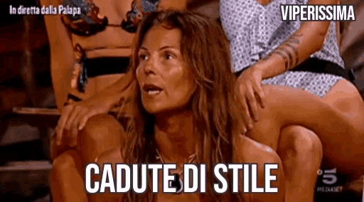 a woman in a bikini sits on a man 's lap with the words cadute di stile written below her