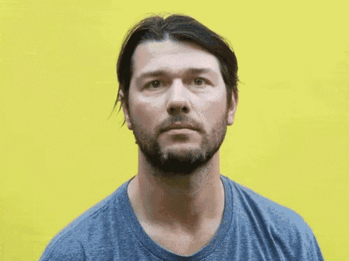 a man with a beard is wearing a blue shirt and looking at the camera