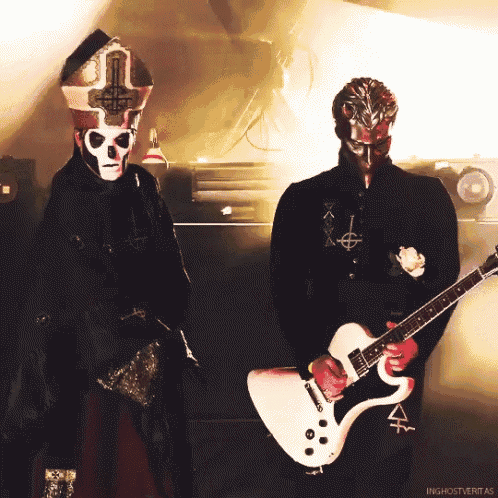 a man in a skull mask holds a white guitar next to another man