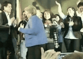 a woman in a blue jacket is dancing in a crowd of people