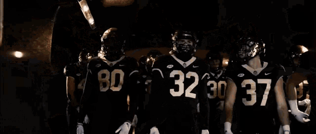 a football player with the number 2 on his jersey stands in a huddle
