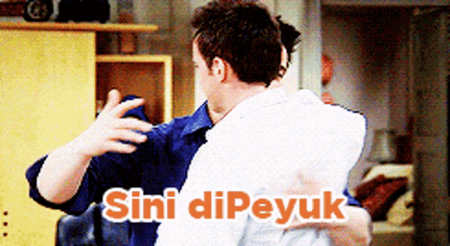 two men hugging each other with the words " sini dipeyuk " on the bottom right
