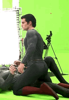 a man in a superhero costume is kneeling on another man 's lap .