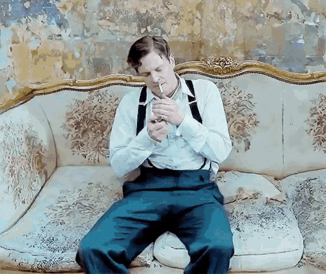 a man is sitting on a couch smoking a cigarette and holding a lighter .