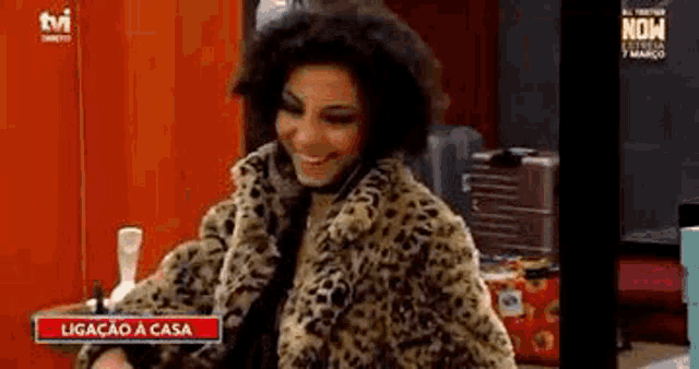 a woman in a leopard print fur coat is smiling and talking on a phone .
