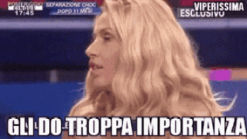 a woman with blonde hair is standing in front of a blue background and says gli do troppa importanza .