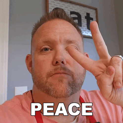 a man making a peace sign in front of a sign that says " peace "