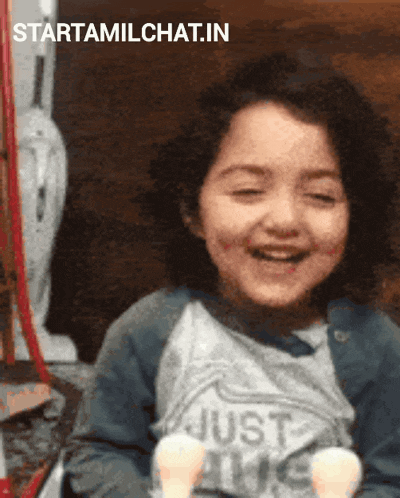 a little girl is smiling and wearing a shirt that says just love