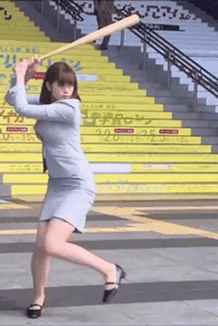 a woman in a business suit is swinging a bat in front of a set of yellow stairs