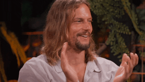 a man with long hair and a beard is smiling