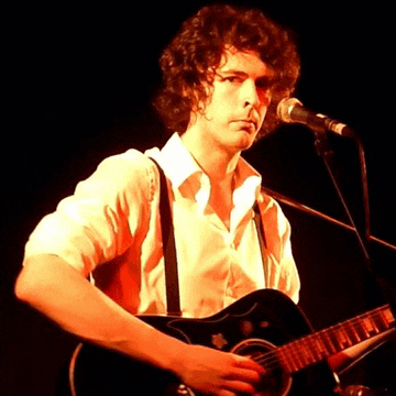 a man is singing into a microphone while holding a guitar