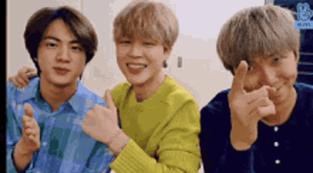 three young men are standing next to each other and giving a thumbs up sign .