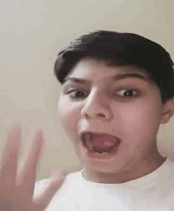 a young boy is making a funny face with his mouth open and his hand out .