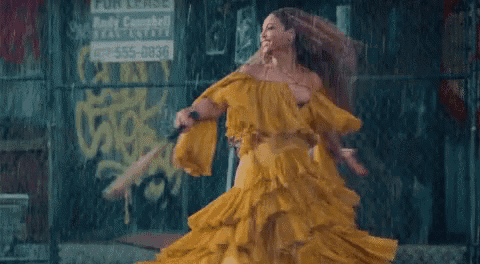 a woman in a yellow dress is running in the rain with a baseball bat .