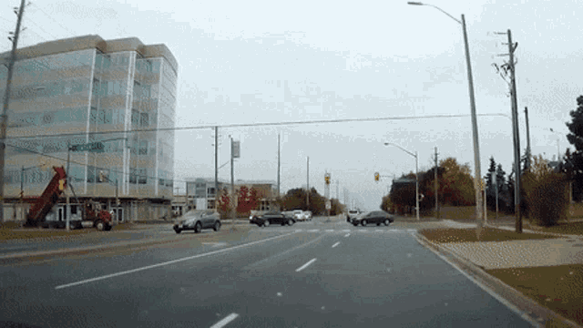 a car is driving down a street with a building in the background and a sign that says ' downtown ' on it