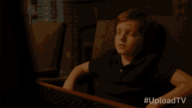 a young boy sits in front of a computer screen with the hashtag #uploadtv on the bottom