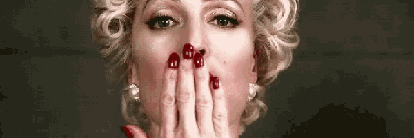 a woman with red nails is covering her face with her hands