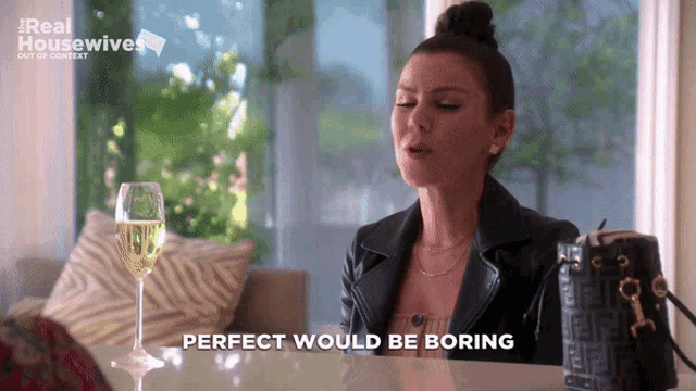 a woman sitting at a table with a glass of wine and the words perfect would be boring above her