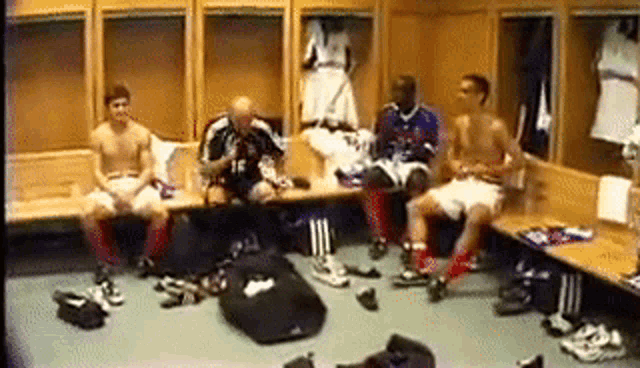 a group of soccer players are sitting in a locker room with their shirts off .