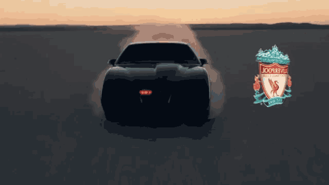a car is driving through the desert and the logo for liverpool is on the bottom